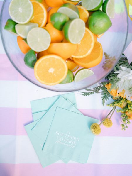 bowl of cut citrus fruit on pink white striped tablecloth with napkins
