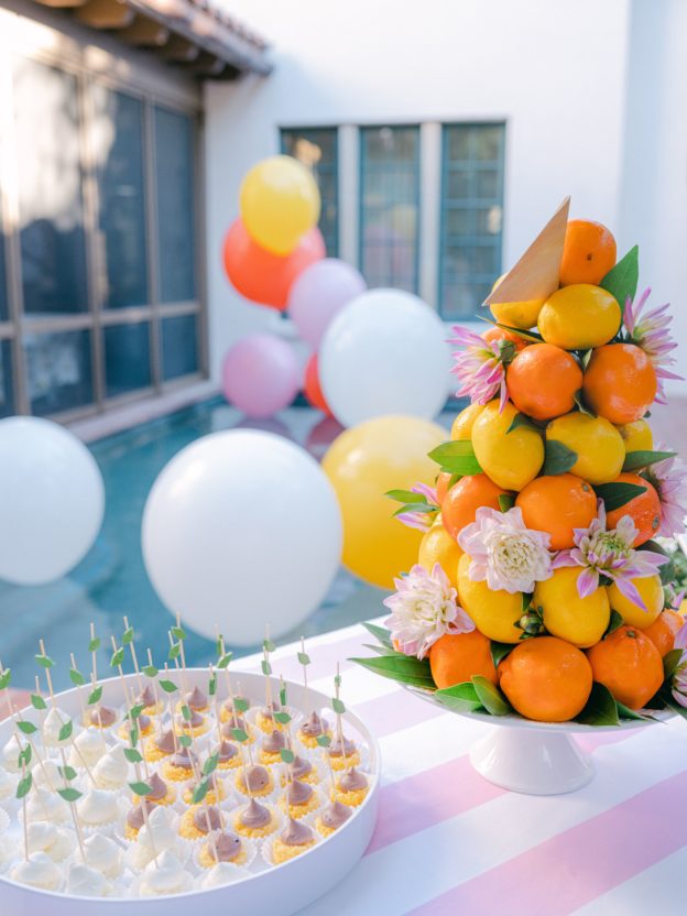 citrus party by the pool with cake bites and balloons