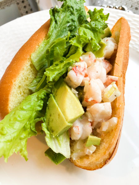 shrimp roll on brioche bread with green leaf lettuce and avocado slices