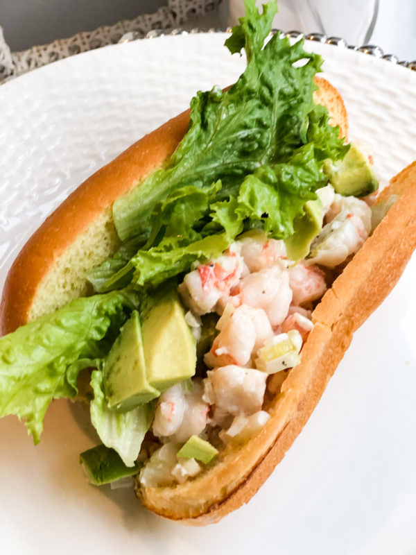 shrimp roll with green lettuce and avocado slices on brioche bread