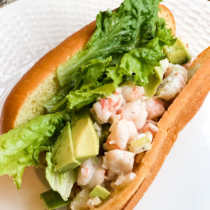 shrimp roll with green lettuce and avocado slices on brioche bread