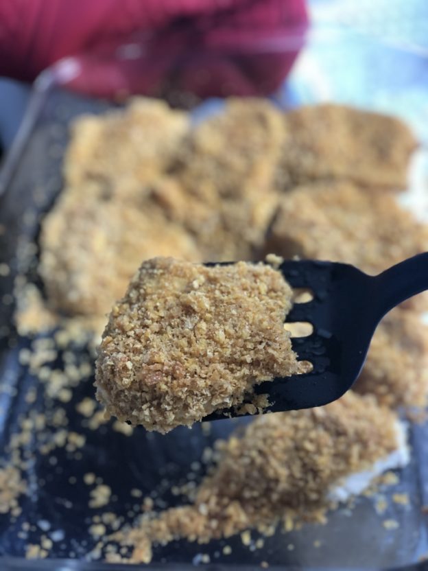 cornflake friend chicken on black spatula in clear dish