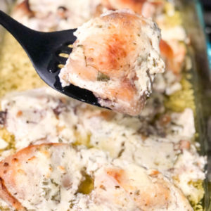 baked chicken thighs marinated with plain yogurt in casserole dish with one piece being held on a black spatula