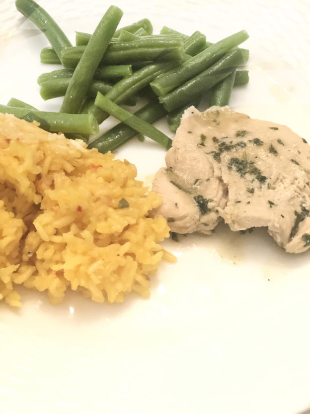 chicken thighs topped marinated in lime and cilantro with green beans and rice on a white plate