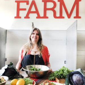 karma farm founder McCall standing behind her plates of chickpea pasta, herbed chicken with kale, and cabbage