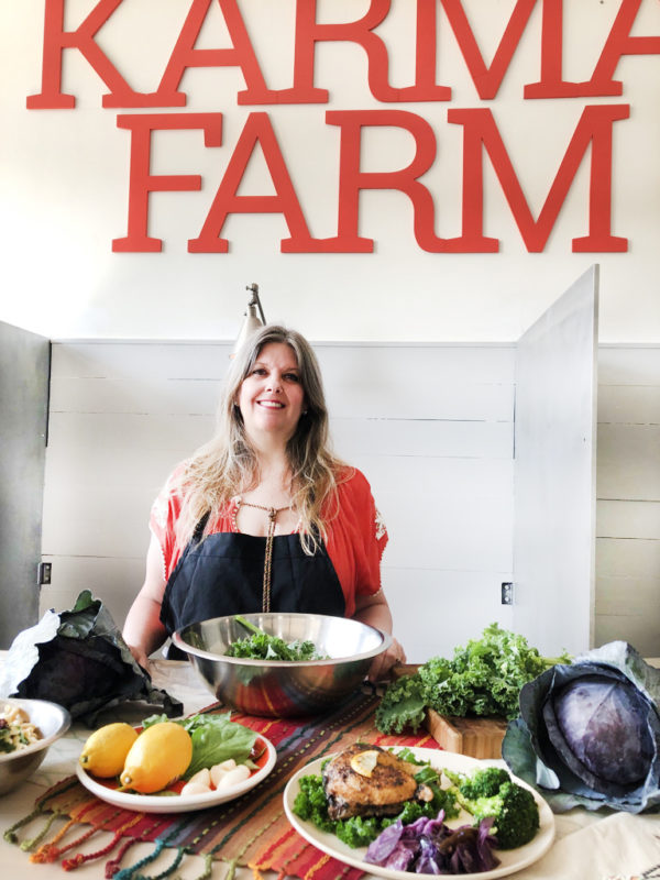 karma farm founder McCall standing behind her plates of chickpea pasta, herbed chicken with kale, and cabbage