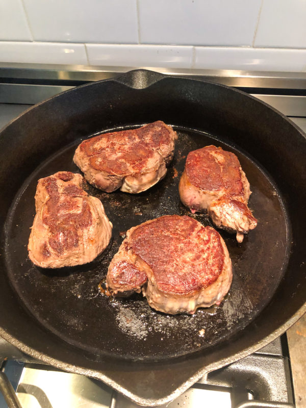 four steaks cooked in cast iron pan