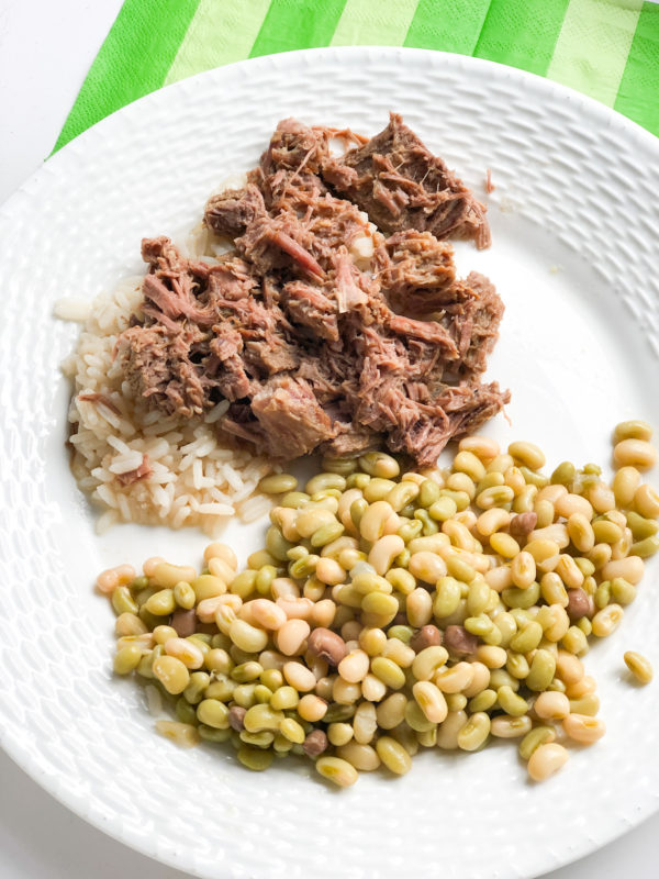stew beef on white rice with lady peas on white plate