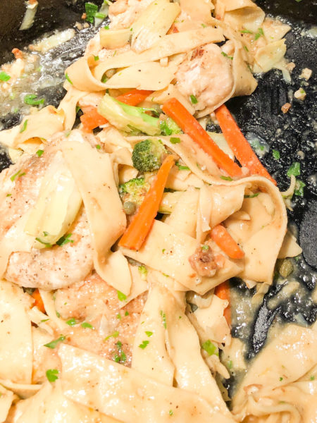 chicken piccata cooking in a cast iron skillet