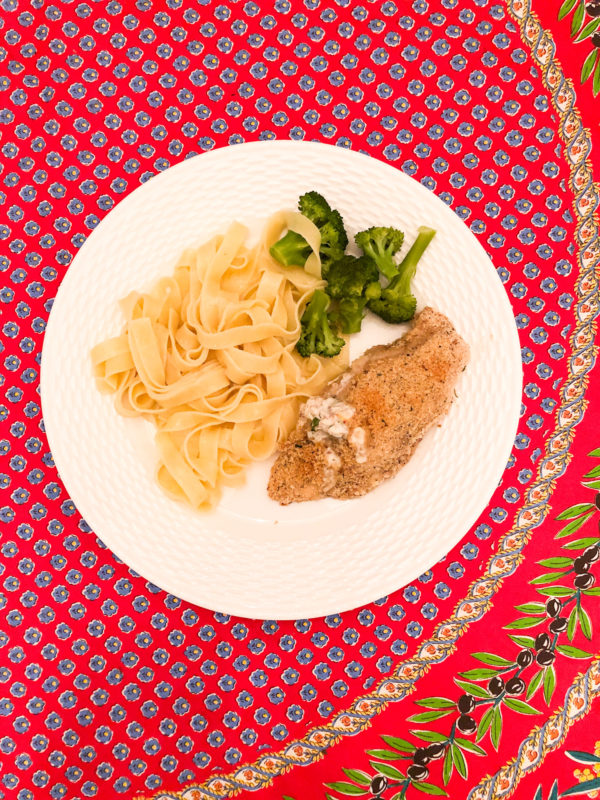 chicken with cream cheese broccoli and egg noodles on white plate and red floral tablecloth
