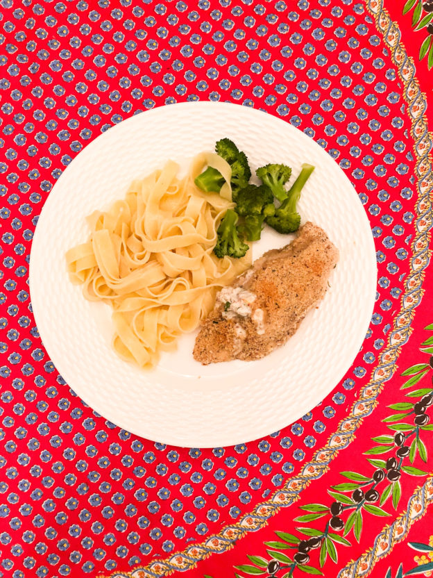 chicken with cream cheese broccoli and egg noodles on white plate and red floral tablecloth