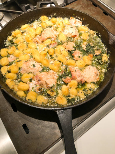 chicken gnocchi and spinach in a black cast iron skillet
