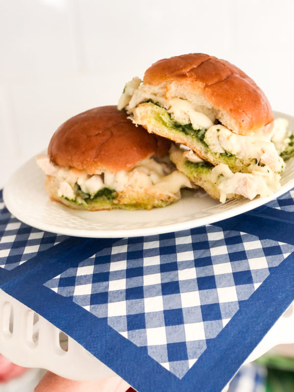 chicken pesto sliders with cheese on white plate and blue gingham napkin