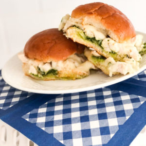 chicken pesto sliders with cheese on white plate and blue gingham napkin