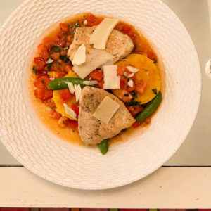 roasted chicken with polenta cakes and tomato sauce on white plate on table with mirrored top