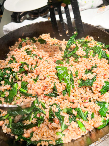 farro with black eyed peas and collard greens being cooked in black skillet
