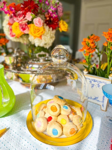 colorful thumbprint shortbread cookies stacked on plate and covered with a cloche