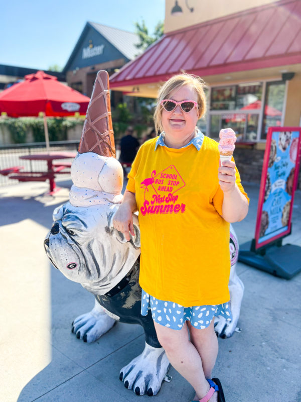 Woman wearing the "School Bus Stop Ahead, Next Stop Summer" Tee while wearing sunglasses and holding an ice cream cone.