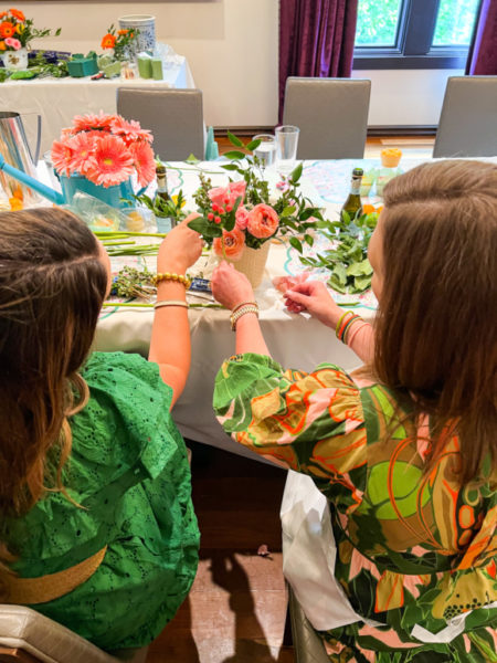 2 ladies making a flower arrangement together seated side by side holding flower stems