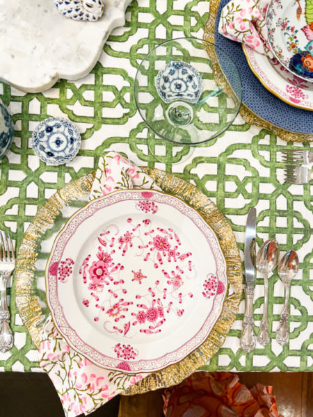 table setting overhead shot with green and white table cloth and pink and white plates