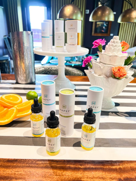 hapsy cbd oil on display on cake stand and surrounded by citrus slices