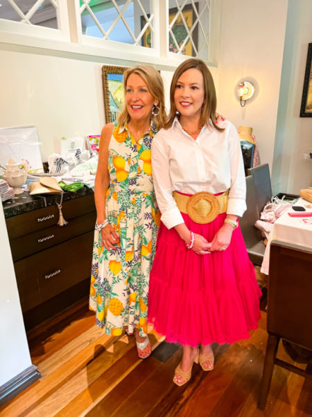 blonde lady in citrus dress and brunette lady in white shirt and bright pink skirt