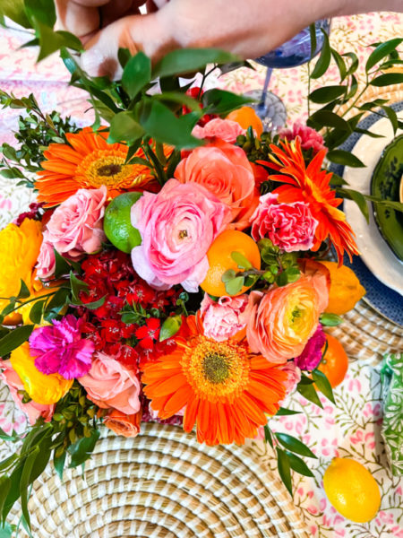 pink orange and yellow flowers being arranged on table