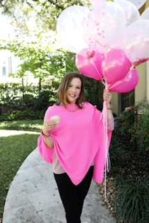 brunette lady holding cupcake with vanilla frosting and a bouquet of pink and white balloons