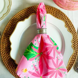 pink and green christmas napkin on white plate and bamboo charger