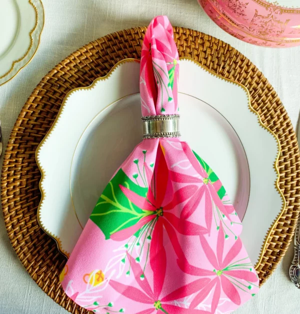 pink and green christmas napkin on white plate and bamboo charger