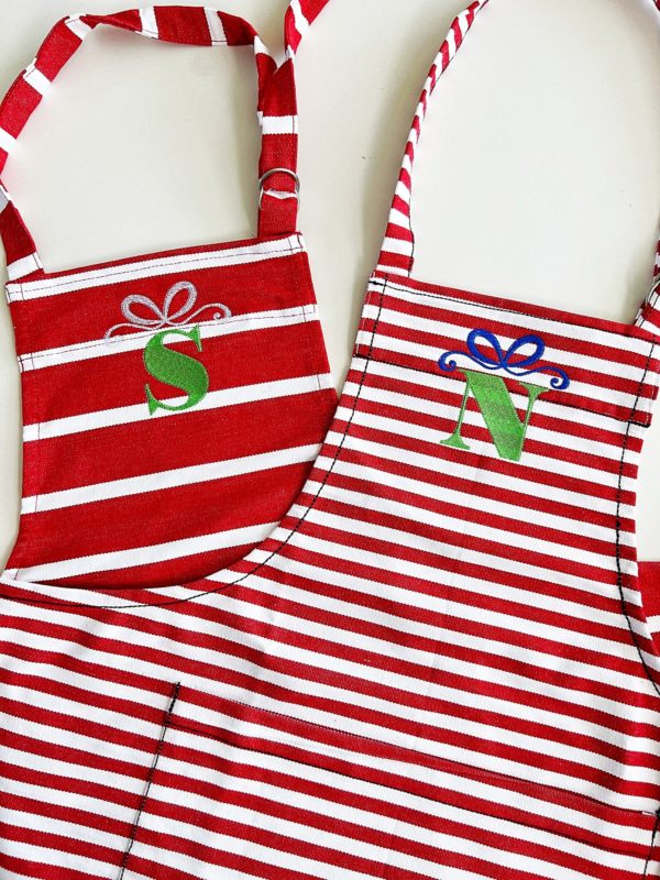 red and white striped aprons with green letter monogram and blue bow on top