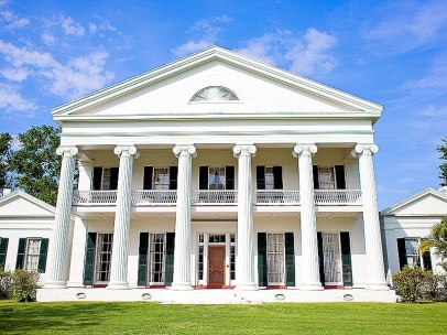 large white historical home with six columns and red front door in louisiana
