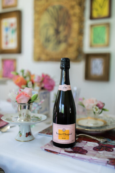 bottle of champagne on mothers day table with flowers and art in background