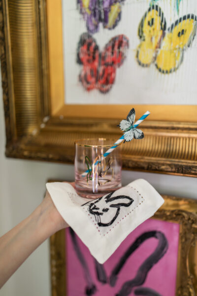 bunny glass with straw with butterfly attached to straw being held in front of butterfly painting