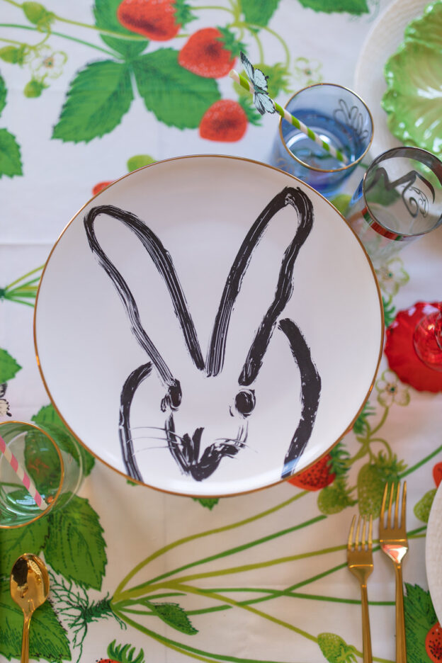 black and white bunny plate on top of cake stand placed on strawberry themed fabric