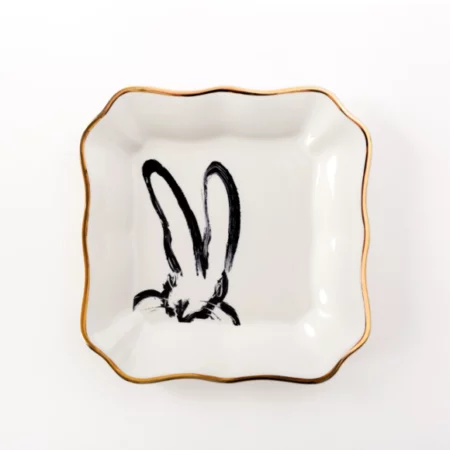 square small white plate with ruffled edges and a whimsical black bunny painted on it