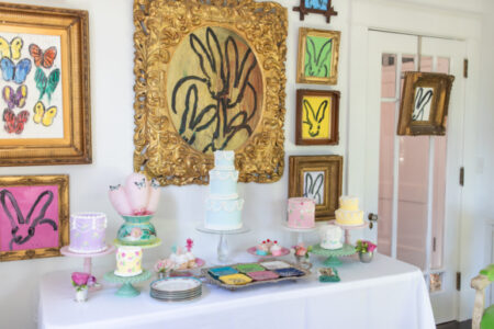 mothers day dessert table with lots of cakes and art on the wall